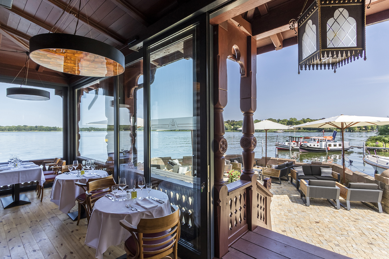 Restaurantterrasse mit gedeckten Tischen, Sonnenschirmen und Blick auf den See.