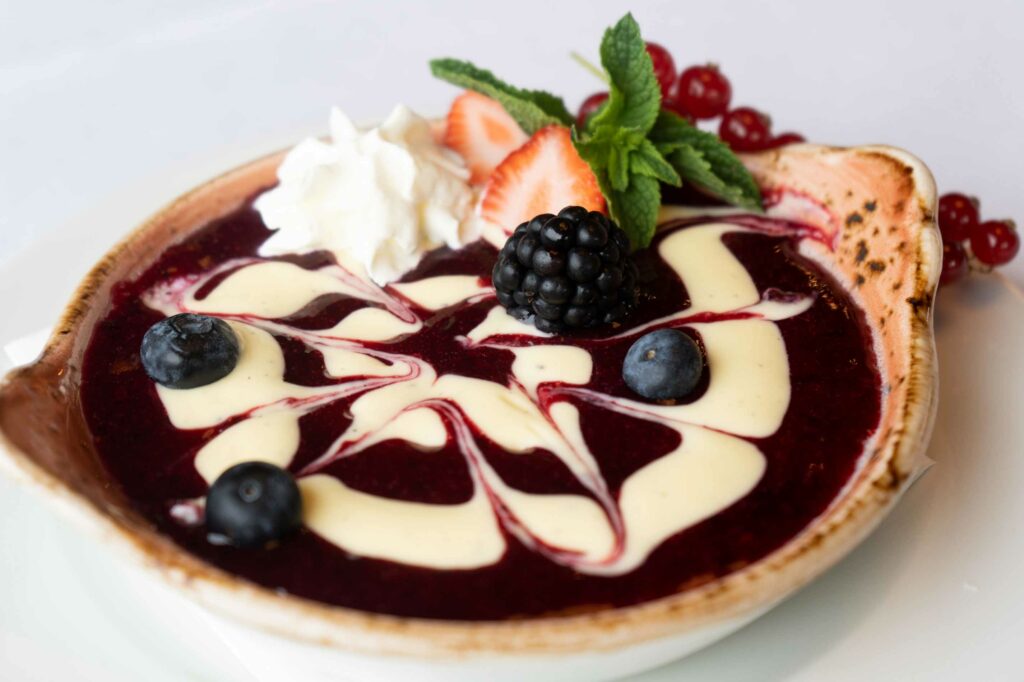 Dessertteller mit Schokoladensauce, Sahne, Früchten und feiner Garnitur.