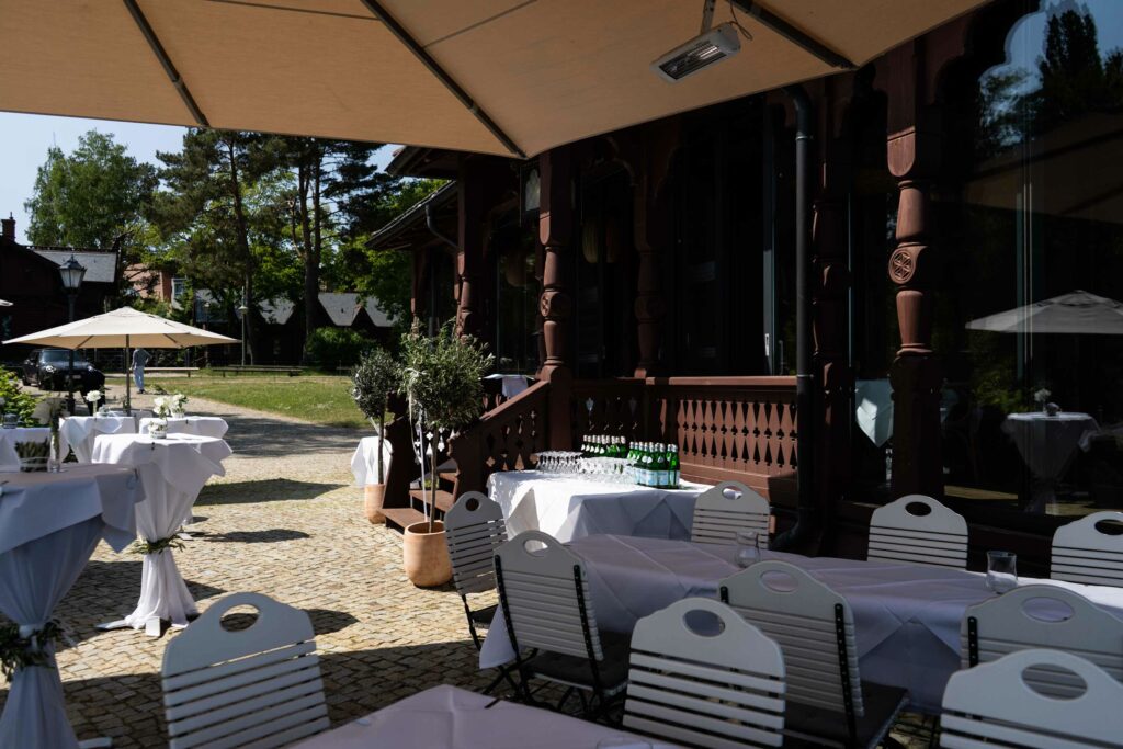 Seeterrasse mit gedeckten Tischen, Sonnenschirmen und Blick auf das Ufer.