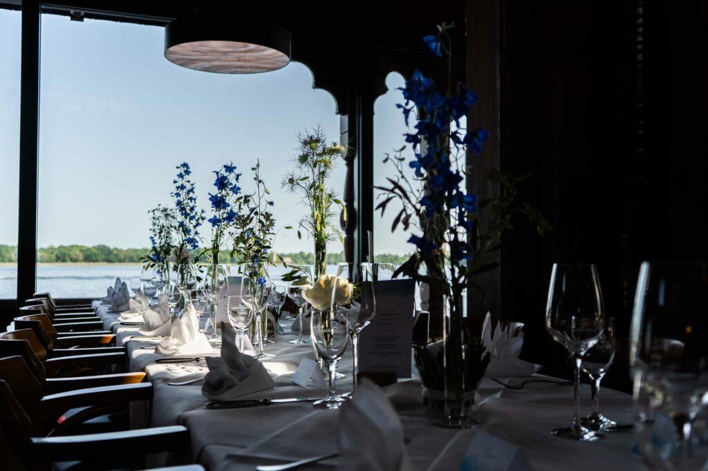 Heller Restaurantbereich mit gedeckten Tischen, Glasfronten und Seeblick.