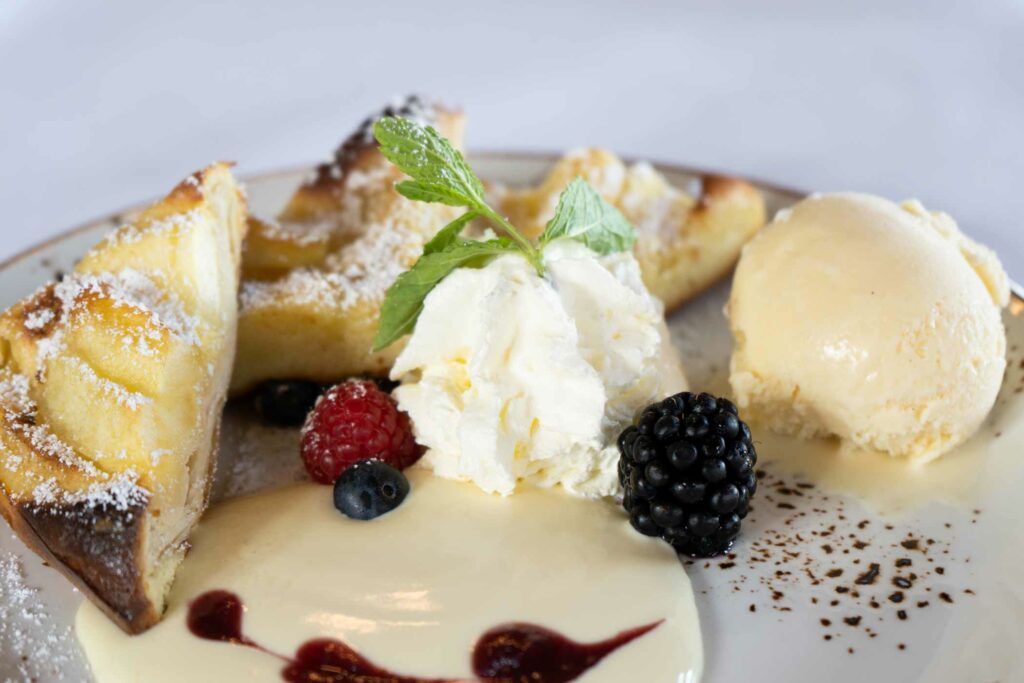 Dessertteller mit Eis, Früchten, Gebäck und Beerensauce.
