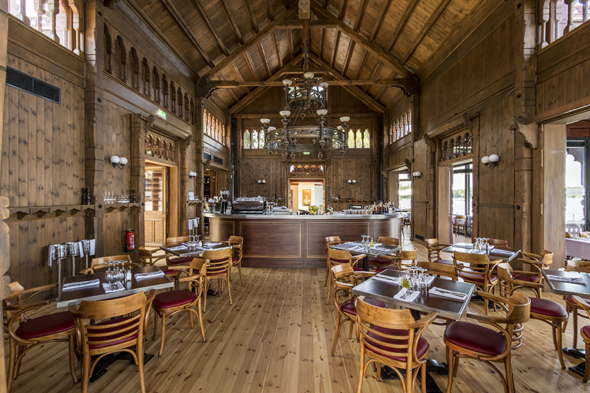 Historischer Restaurantsaal mit Holzmöbeln, hoher Holzdecke und eingedeckten Tischen.