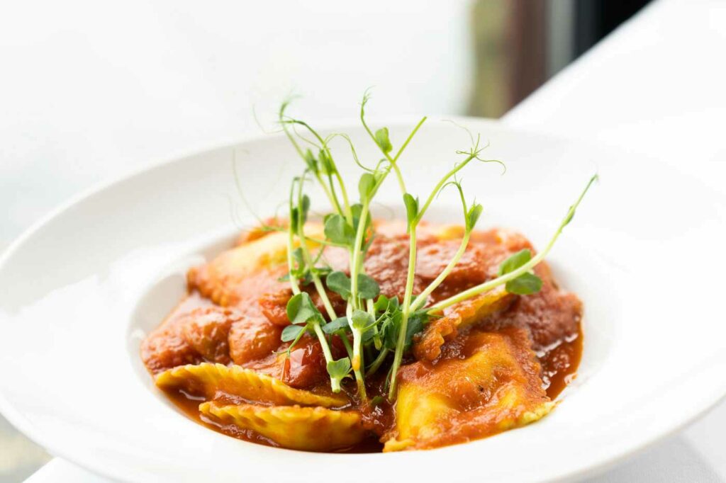 Garnelengericht mit Sauce, Kräutern und Gemüse in einem weißen Teller.