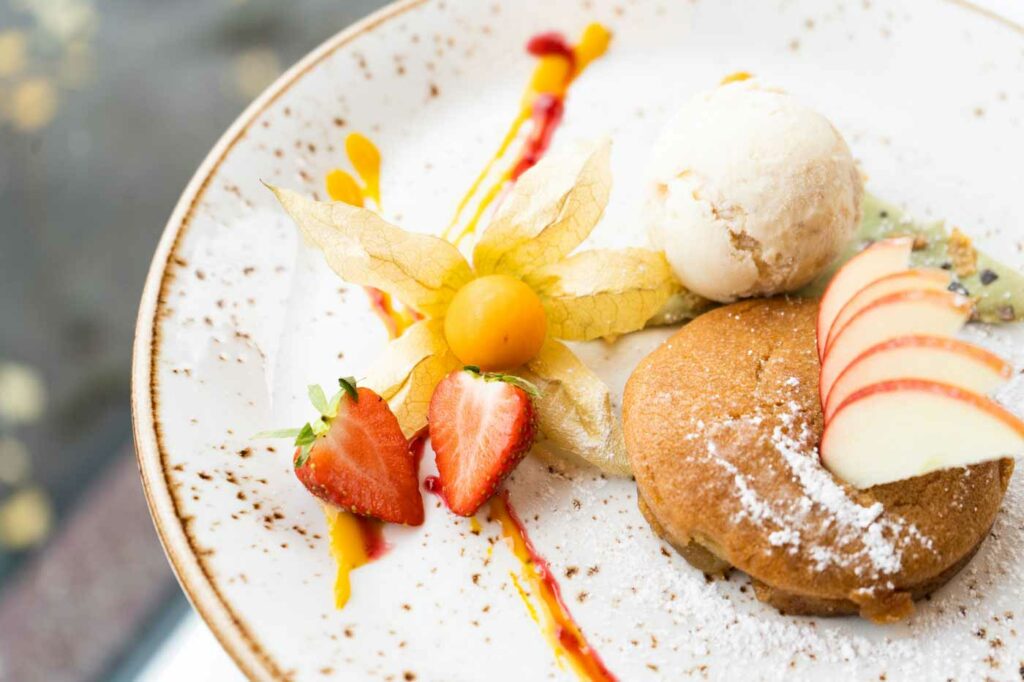 Dessertvariation mit Sorbet, Eis, Früchten und feiner Sauce auf einem Teller.