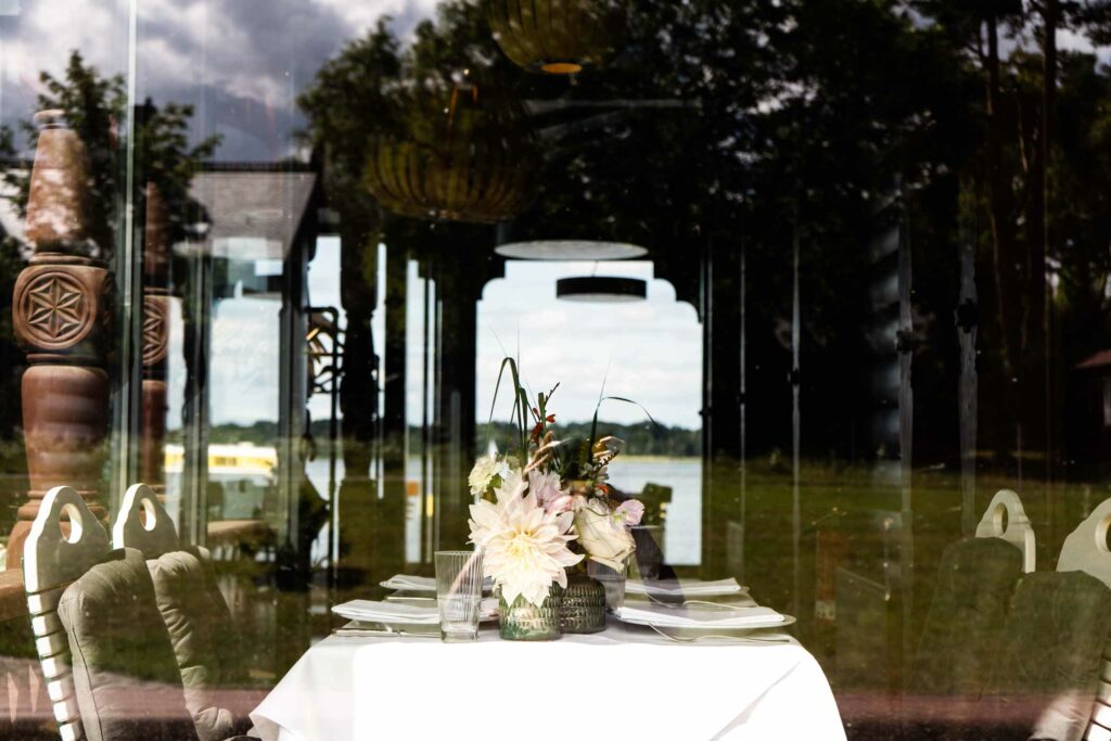 Gedeckter Tisch im Außenbereich mit Blick auf Wasser und Bäume.