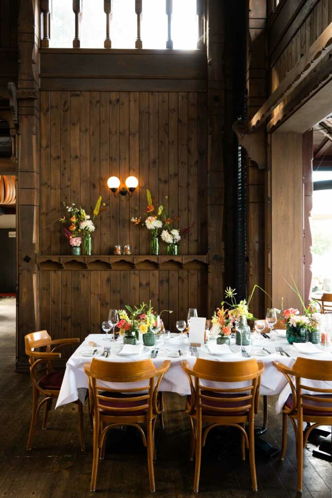 Restaurantinnenraum mit festlich gedeckten Tischen, Blumen und warmem Licht.
