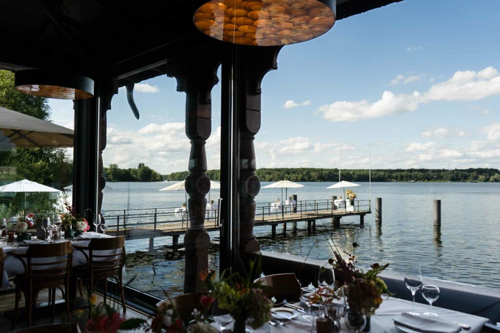 Festlich gedeckte Restaurantterrasse mit Blick auf den See, Steg und Segelboote.